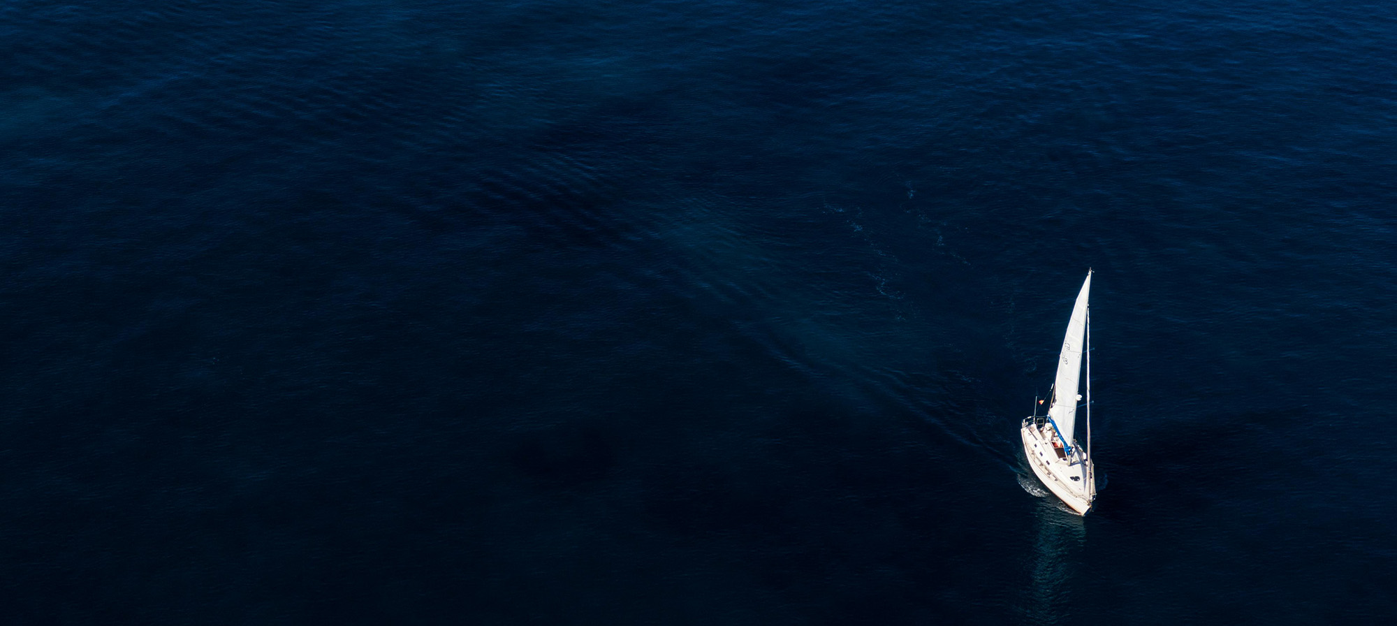 A white sailboat making its way across deep blue water